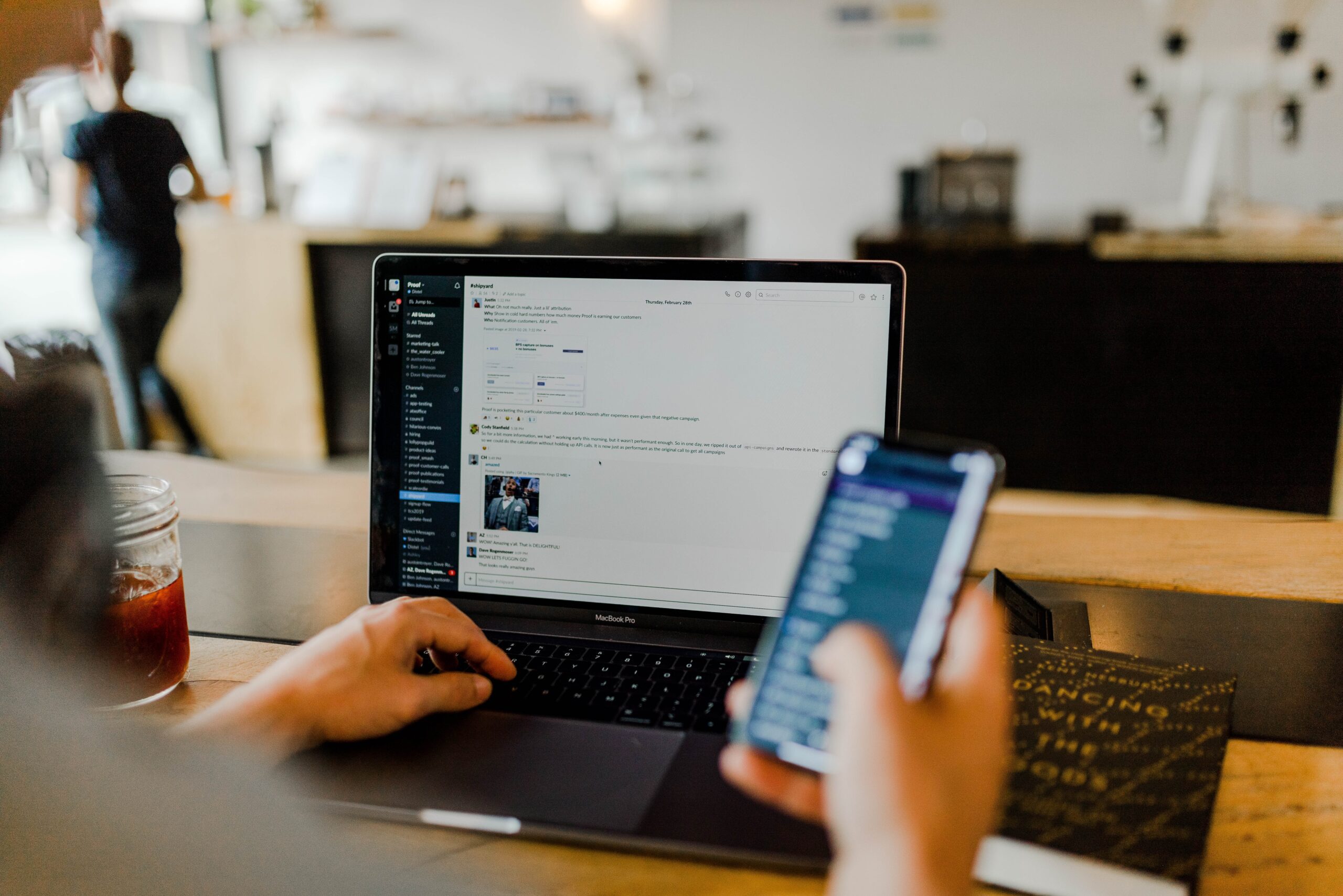 A man holding phone, sitting on the laptop and writing article on how to succeed with your outsourcing partner.