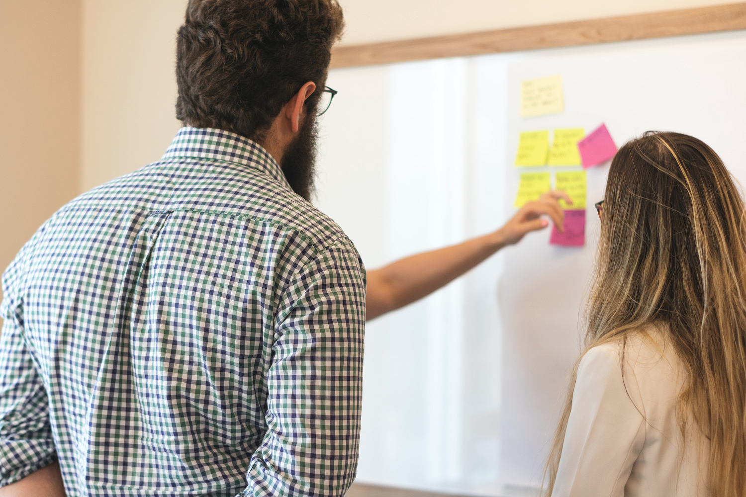 A man and woman Spotting Applicant Vetting Mistakes On Sticky Notes and Placed on A Board