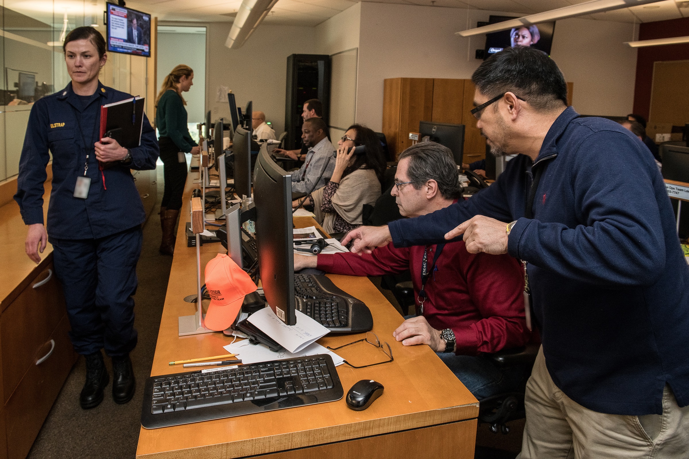 Exceptional Team Sitting on desks in front of computers and one is passing in an aile