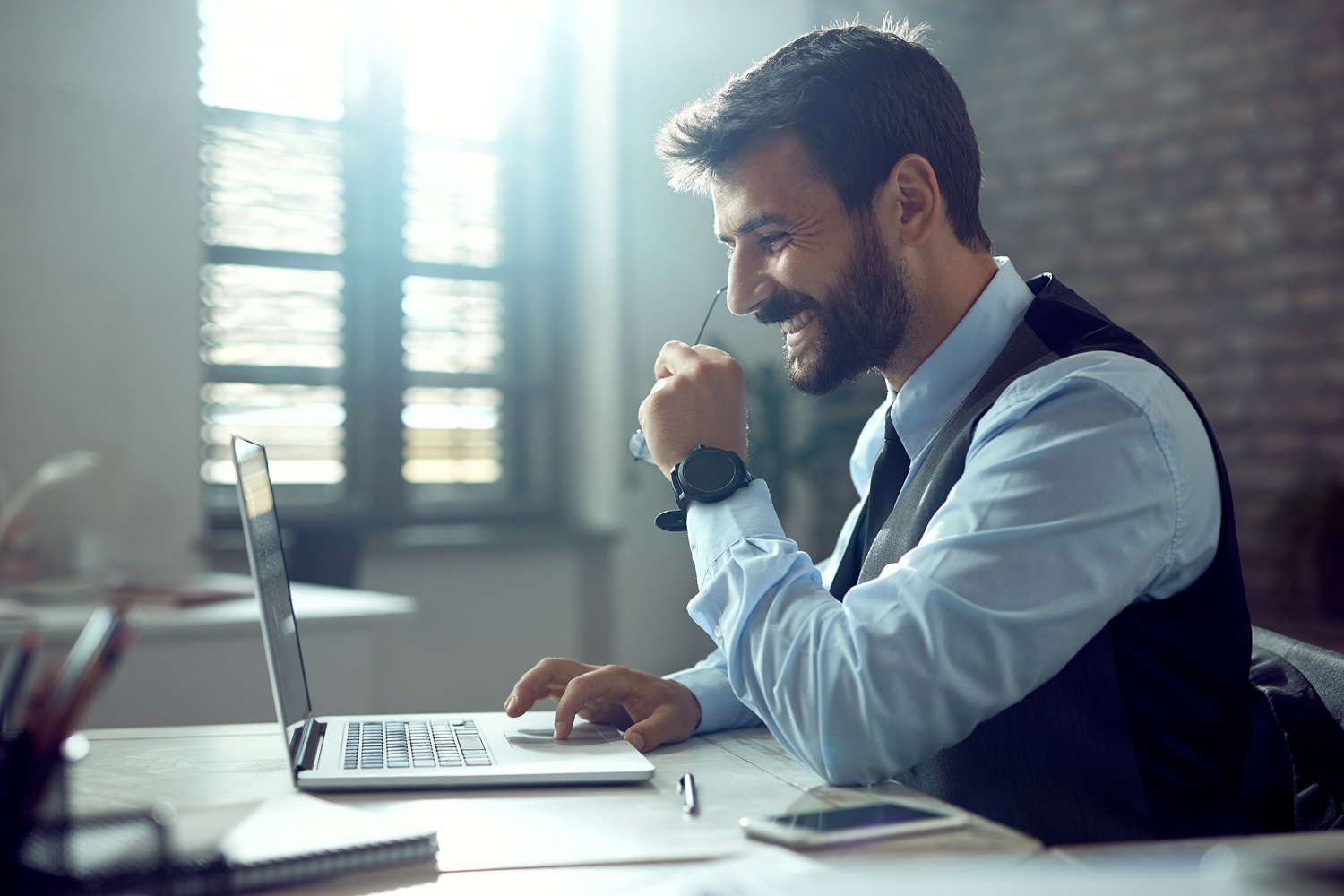 Side view of happy businessman using computer while working in the office.